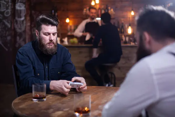 Dos hipsters barbudos jugando un juego de cartas en un pub —  Fotos de Stock