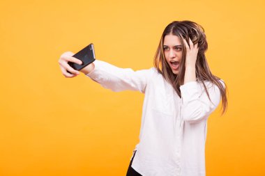 Mutlu genç kız sarı arka plan üzerinde bir selfie yapma