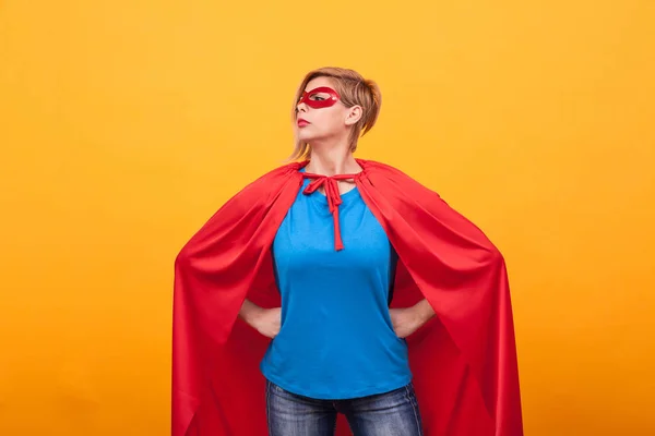 Junge Frau im Superhelden-Kostüm steht stolz über gelbem Hintergrund — Stockfoto