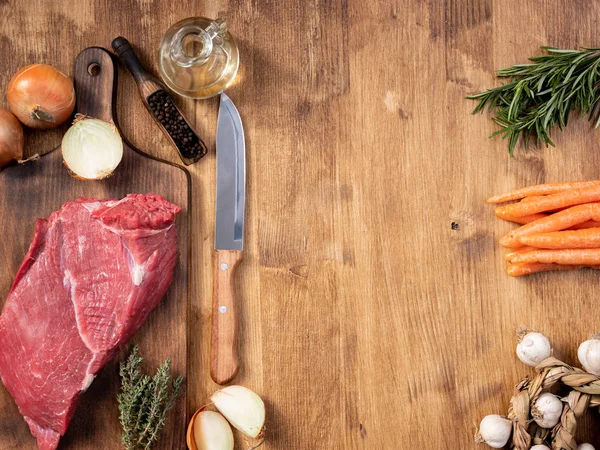 Couteau de chef à côté d'un gros morceau de légumes frais de viande rouge — Photo
