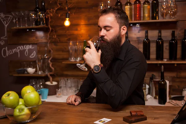 Joven camarero tatuado con gran barba degustando una copa de vino . —  Fotos de Stock