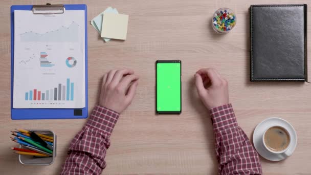 Visão superior de mãos masculinas rolando na borda direita de um telefone inteligente com tela verde em — Vídeo de Stock