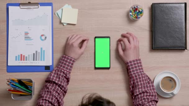 Pohled shora mužských rukou posouvání na horní hraně smartphonu s zeleným plátnem na — Stock video