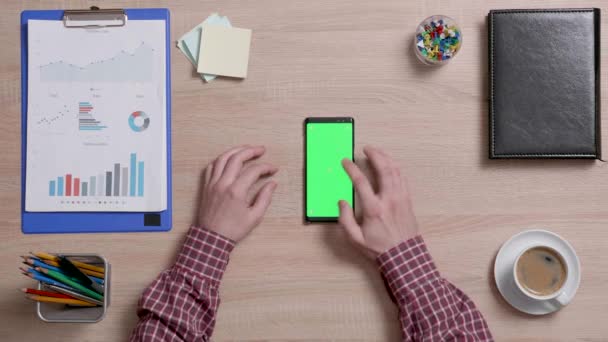 Vue du dessus d'un mans mains toucher le centre d'un écran vert sur un téléphone intelligent — Video