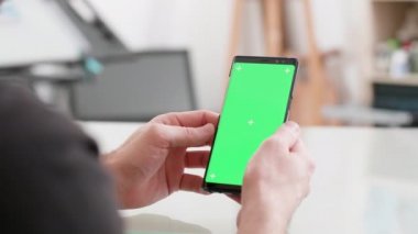 Adam bir masada oturur yeşil ekran ile onun Smartphone tutar