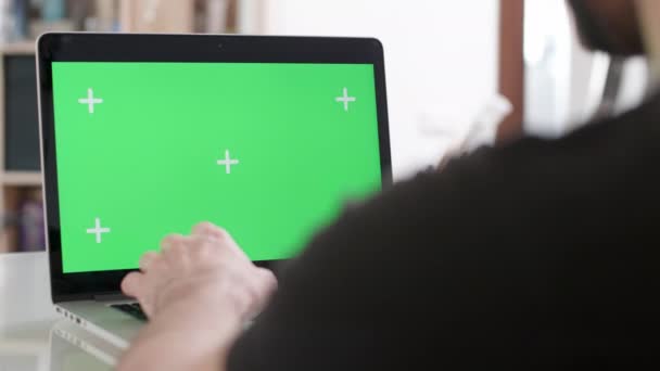 Schieberegler über die Schulter eines Mannes geschossen, der an seinem Laptop mit grünem Bildschirm arbeitet — Stockvideo