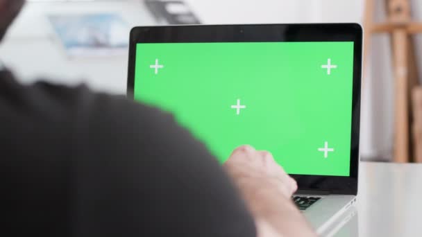 Man werkt op een laptop met een groen scherm display — Stockvideo