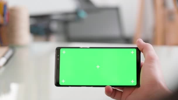 Άνθρωπος κρατώντας οριζόντια ένα smartphone με πράσινη οθόνη στο — Αρχείο Βίντεο