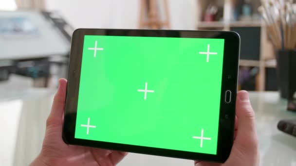 Segurando um tablet com tela verde em uma oficina de artistas — Vídeo de Stock