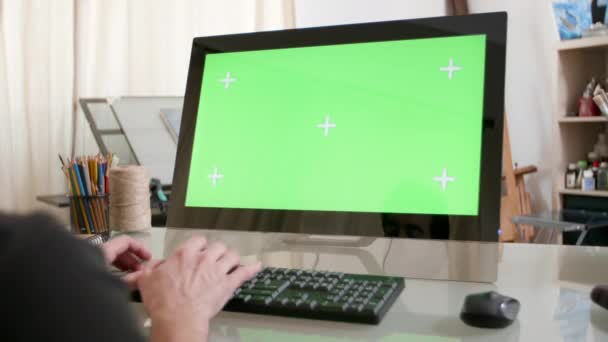 Hombre escribiendo un texto en su teclado con una pantalla verde en su monitor — Vídeos de Stock