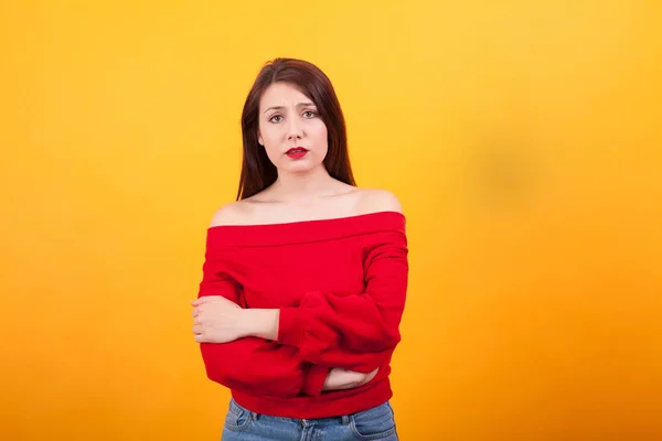 Portrait d'une jeune fille occasionnelle bouleversée debout avec les bras croisés sur fond jaune — Photo