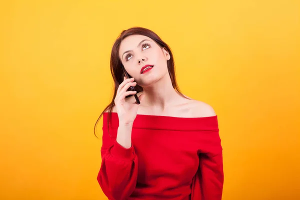 Sarı arka plan üzerinde telefonda konuşurken güzel genç kadının portresi sıkılmış — Stok fotoğraf