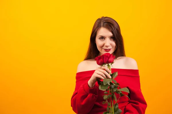 Romantische jonge vrouw met rode rozen over gele achtergrond — Stockfoto