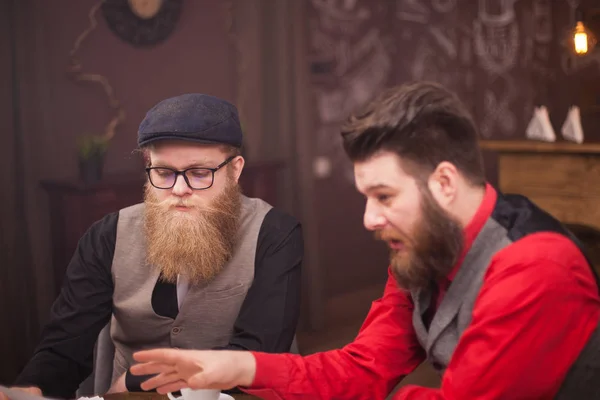 Young bearded men showing to his boss something on his laptop — Stock Photo, Image