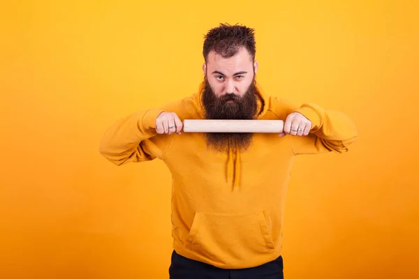 Cool barbu homme en utilisant la pagaie de cuisine et en regardant la caméra sur fond jaune — Photo