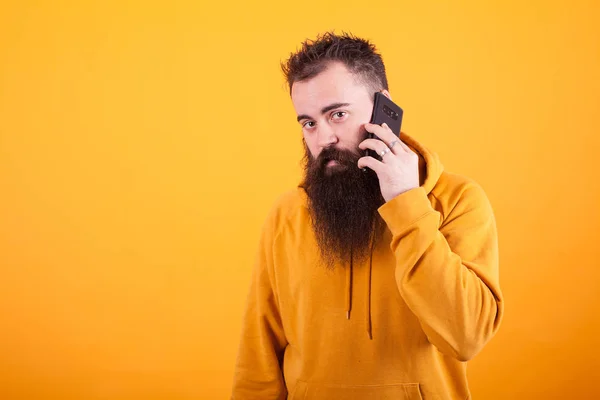 Ο μουσάτος τύπος που κοιτάζει ανήσυχος στην κάμερα ενώ μιλάει στο τηλέφωνο πάνω από κίτρινο φόντο — Φωτογραφία Αρχείου