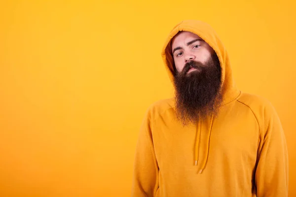 Retrato de homem barbudo olhando serios para a câmera sobre fundo amarelo — Fotografia de Stock