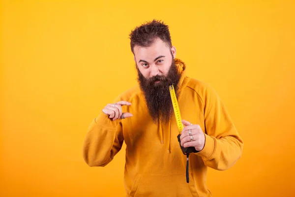 Engraçado barbudo homem mostrando dimensão na roleta sobre fundo amarelo . — Fotografia de Stock