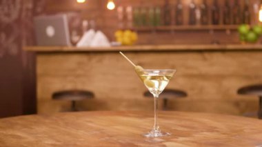 Arka planda bar sayacı ile boş bir ahşap masada bir martini cam Parallax atış