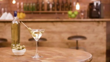 Tahta bir masada zeytin ile bir şişe ve martini bir bardak Sürgü çekim