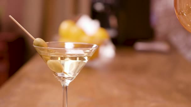 Зеленые оливки в стакане мартини на барной стойке — стоковое видео