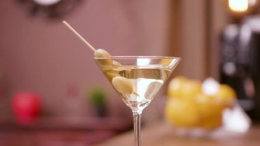 Zeytinle süslenmiş martini bardağının paralaks çekimini kapatın