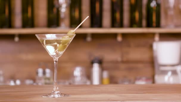 Slider shot of a glass of martini over a bar background — Stock Video