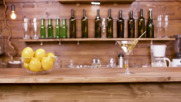 Slider shot of a glass of martini beverage on a bar background — Stock Video