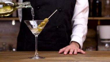 Barmen yavaş çekimde bir kokteyl bardağına martini döküyor