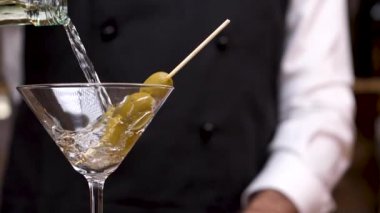 Barmen el yavaş hareket te bir kokteyl bardağına martini dökme