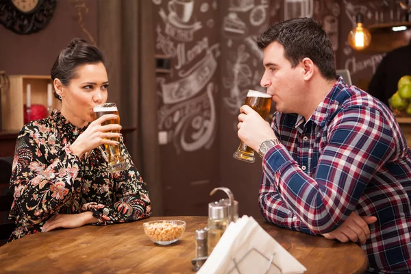 Casal romântico bebendo cerveja em um pub hipster e fazendo um brinde . — Fotografia de Stock