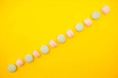 Sarı arka planda geleneksel Fransız renkli macaroons