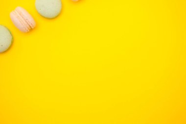 Sarı arka planda renkli makarna veya makaron üst görünümü