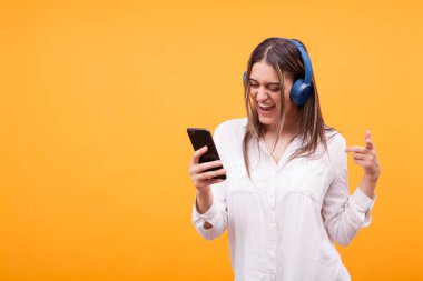 Güzel kız telefonunda tarama ve kulaklık müzik dinlerken
