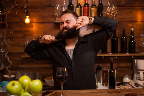 Barman barbudo sendo engraçado com sua barba atrás do balcão . — Fotografia de Stock