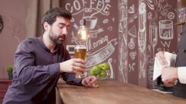 Bir bar tezgahında Adam bir bira çalışır ve iyi tat onaylar