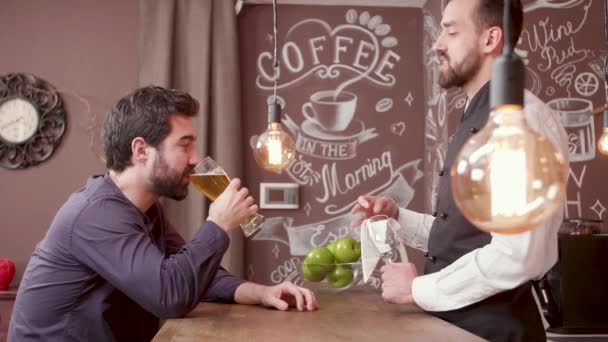 Jeune homme barbu raconte une histoire au barman et boit de la bière — Video