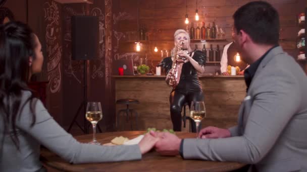 Female musician performing a romantic song for a couple in a restaurant — Stock Video