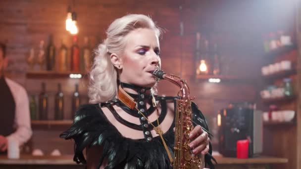 Portrét mladého samičího saxofonisty, který se zpívá před barem — Stock video