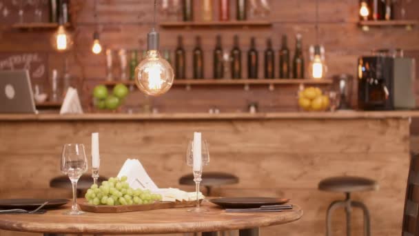 Uma mesa redonda de madeira em um restaurante vazio com queijo e aperitivo de uvas — Vídeo de Stock