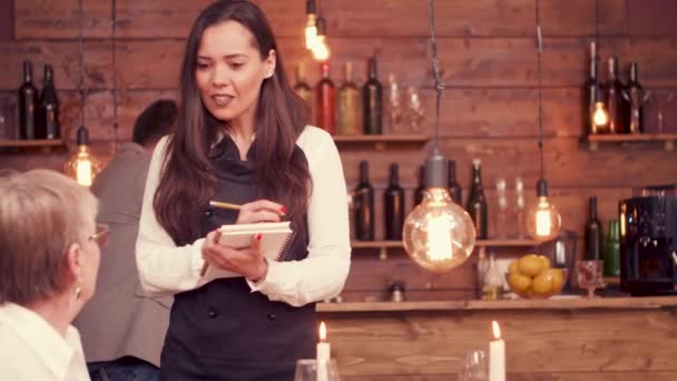 Bela garçonete tomando uma ordem de velha senhora com óculos — Vídeo de Stock