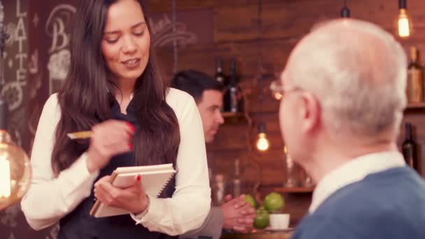 Schöne Kellnerin nimmt eine Bestellung von einem alten Mann mit Brille entgegen — Stockvideo