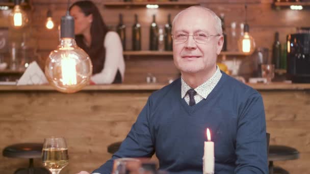 Porträt eines gutaussehenden alten Mannes, der in einer Bar in die Kamera lächelt — Stockvideo