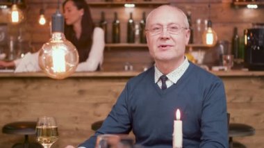 Bir barda kameraya konuşan yakışıklı yaşlı bir adamın portresi