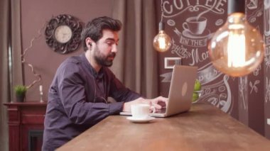 Genç adam internette konuşmak için kulaklıklarını kullanıyor.
