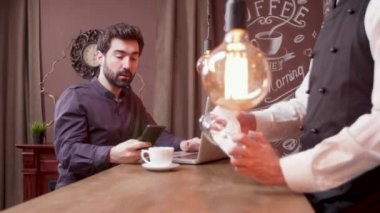 Adam bilgisayarında çalışırken ve kahve içerken bir telefon anına cevap verir