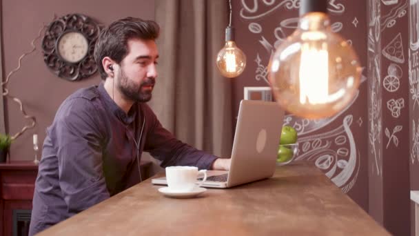 Schöner Mann bei einer Videokonferenz, während er einen Kaffee in einer Bar trinkt — Stockvideo