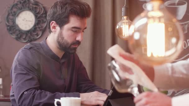 Jeune homme barbu utilisant une tablette à un comptoir de bar — Video