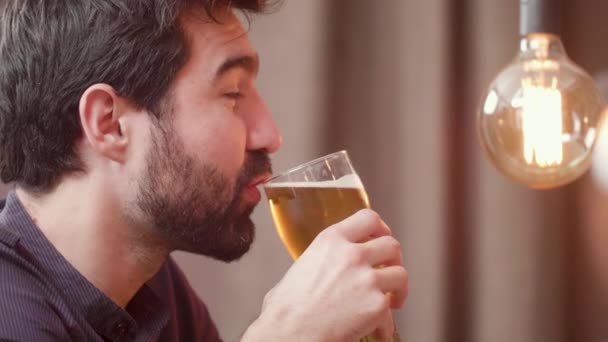 Sakallı genç adam bira içiyor ve barmenle sohbet etmek. — Stok video