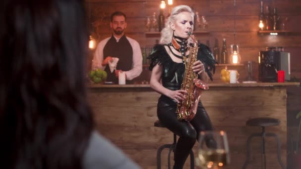 Σέξι γυναίκα παίζει ένα τραγούδι σε ένα σαξόφωνο σε ένα μικρό εστιατόριο — Αρχείο Βίντεο